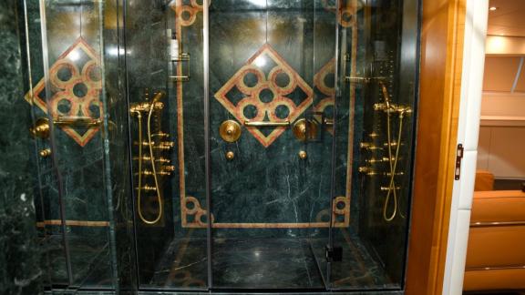 Luxurious dark marble shower with gold fittings and decorative inlays.