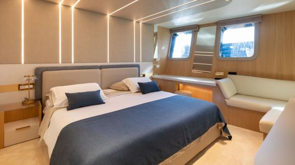 Scorpios Motorsailer features a spacious double bed, seating area and large windows in this bright cabin.