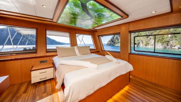 Large bed, wood decor and sea view windows in cabin of Lila yacht near Fethiye.
