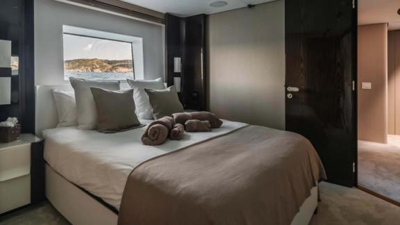 Spacious cabin with modern design on Nemesis yacht, sea view window and cozy bed.