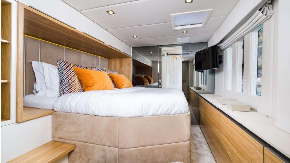 In Kastela the Vulpino cabin features a large bed TV wide windows and orange toned pillows.