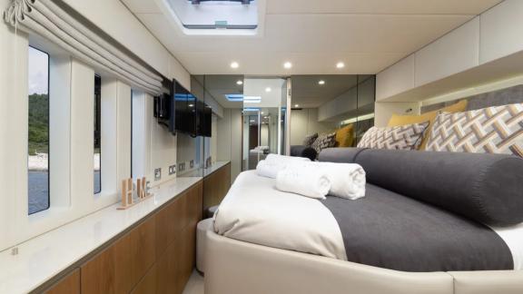 In Kastela Zara’s cabin has a large bed long windows soft lights and a TV on the wall.