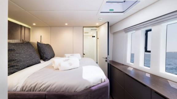 В каюте катамарана Sunreef 50 просторная кровать и панорамный вид на море через большие окна.