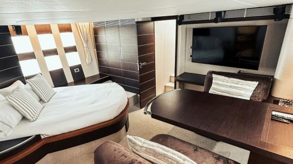 The bedroom on motor yacht Esperanza features a large bed, modern furniture, and a TV, offering a luxurious stay.