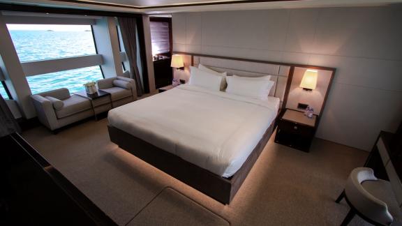 The master bedroom of the Legende motor yacht with large windows offers elegant comfort for a Dubai yacht rental experie