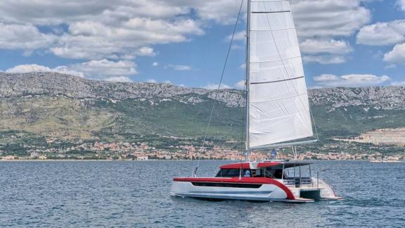 Kırmızı detaylı Luna 49 Red katamaran, arka güvertesiyle görünüyor ve Split kıyılarında yelkenle ilerliyor.