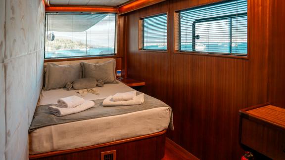 The modern guest cabin of the Oggusto trawler yacht with large windows, wood paneling, and airy design.