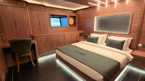 Аренда люкс гулета Oguz Marin в Бодруме предлагает уютную каюту с картинами и деревом для отдыха всех 12 гостей.