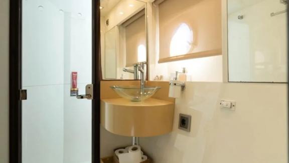 The bathroom on motor yacht Breathe features a modern design, glass sink, and spacious shower.