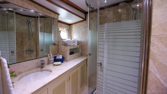 Gazella’s bathroom features a spacious sink, mirrors, and a glass shower cabin.