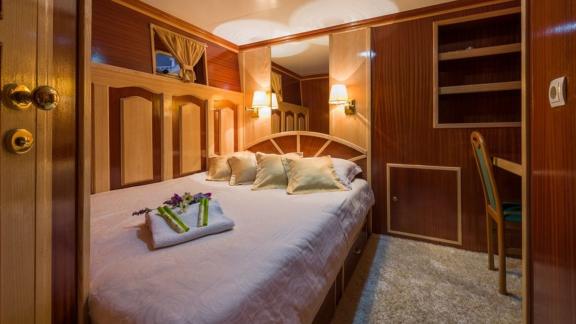 This Korab cabin features a cozy double bed and elegant wooden panel details.