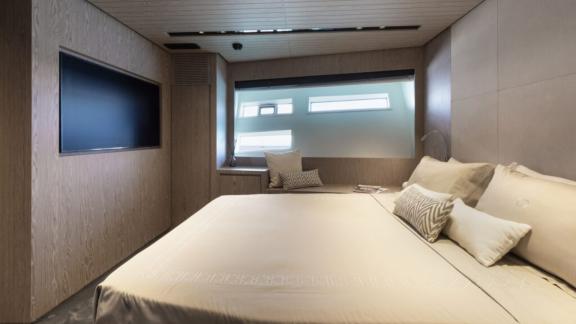 A serene sleeping space with a wide bed, soft tones, and natural light from large windows.