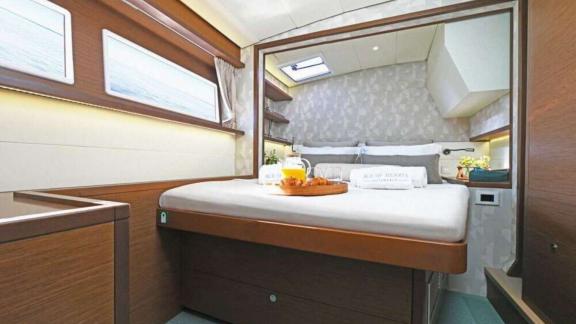 The master cabin of Ace of Hearts in Athens features a large bed, overhead window and wooden finishes.