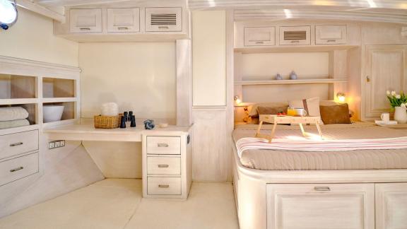 The cabin of White Pearl gulet in Athens includes a double bed, desk area and storage units.