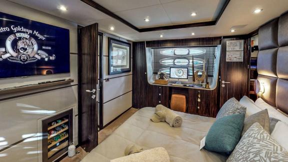 The spacious bedroom on the Ammonite motor yacht offers modern decor and comfortable seating arrangements.