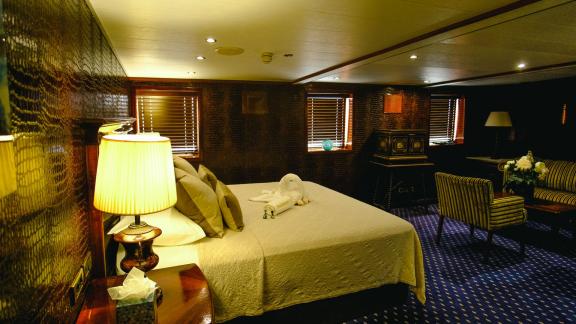 The master suite on the Harmony II yacht features a comfortable bed, elegant decor, and a spacious seating area.