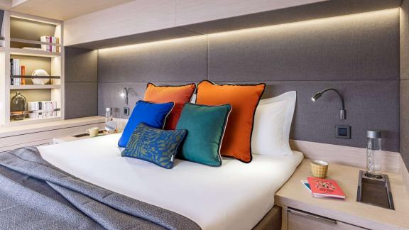 Modern bedroom of catamaran Happy, decorated with stylish and colorful pillows.