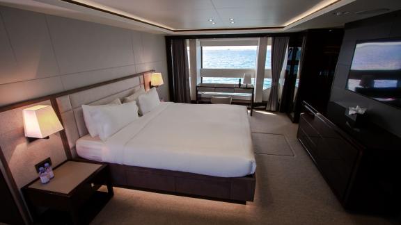 The master bedroom of the Legende motor yacht, featuring large sea-view windows, adds luxury to your Dubai yacht rental