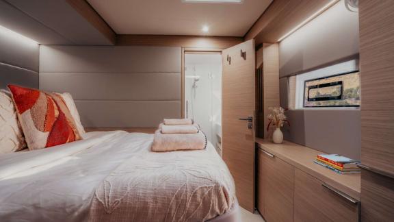 Almosta Road cabin features a cozy bed, window view and open door to the bathroom.