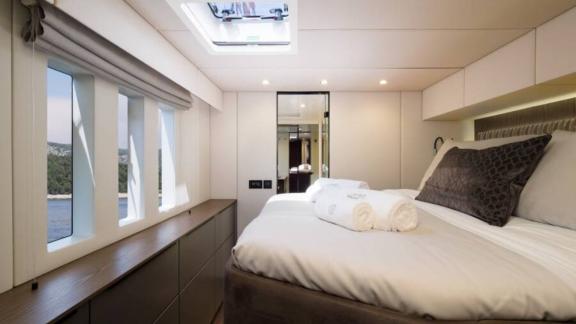 В каюте катамарана Sunreef 50 большая кровать, шкафы и панорамные окна с видом на море.
