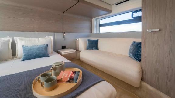 Bright interior with large window, cozy bed, and a soft lounge seat for relaxing.