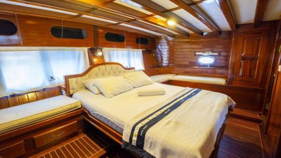 Master cabin of Gulet Cemre Junior with a large bed and comfortable seating area.