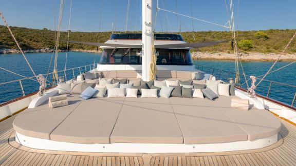 Просторная зона для загара с подушками на палубе Lady Gita с живописным видом на побережье.