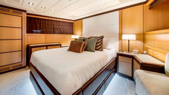 Zu sehen sind ein Doppelbett, ein Arbeitsbereich und das elegante Design der Gästekabine der Daya.