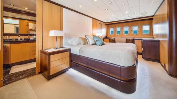 Zu sehen sind das große Bett, der Sitzbereich und der Zugang zum privaten Bad der Masterkabine.