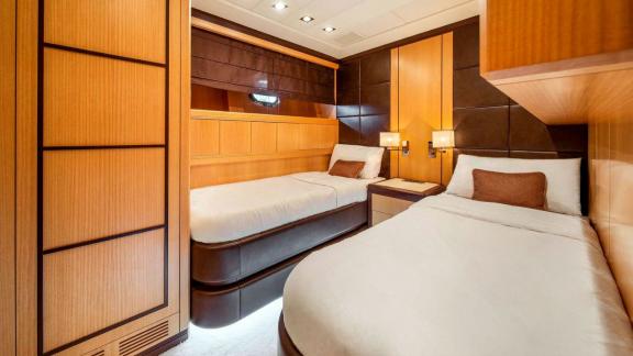 Zu sehen sind zwei Einzelbetten, Nachttische und elegante Holzdetails in der Gästekabine der Daya.