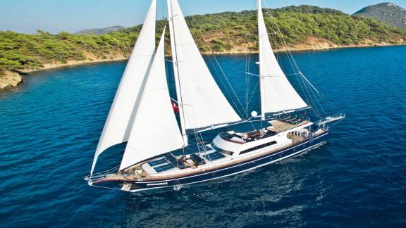 30-meter long charter yacht Maske 2 with 6 luxurious cabins in front of a picturesque coastline.