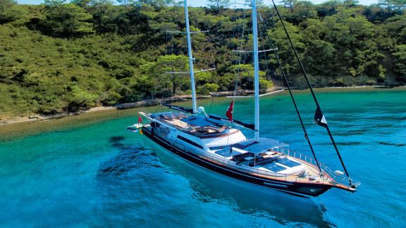 The luxurious charter yacht Maske 2 sailing majestically along a stunning coastline.