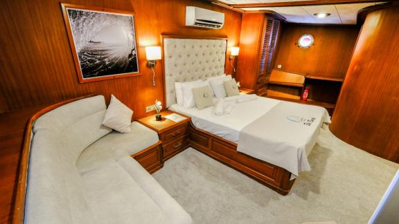 An elegant cabin of the Gulet Efe Burak with a comfortable bed and seating area.