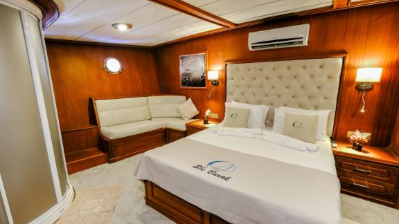 A spacious cabin of the Gulet Efe Burak with a large bed and a cozy sofa.