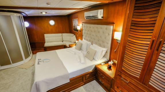 A luxurious cabin of the Gulet Efe Burak with a double bed and seating area.