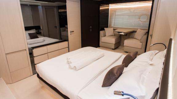 Large bed with elegant linens and a cozy sitting area on a yacht