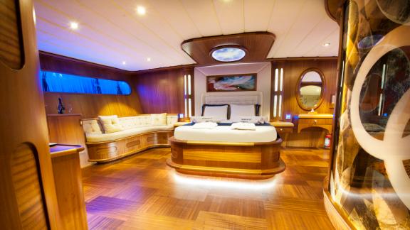 Großes Bett, elegante Holzeinrichtung und gemütliche Sitzecke im Hauptschlafzimmer der Yacht