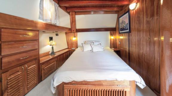 Cosy bedroom on a gulet with wooden interior, double bed and bedside lamps.