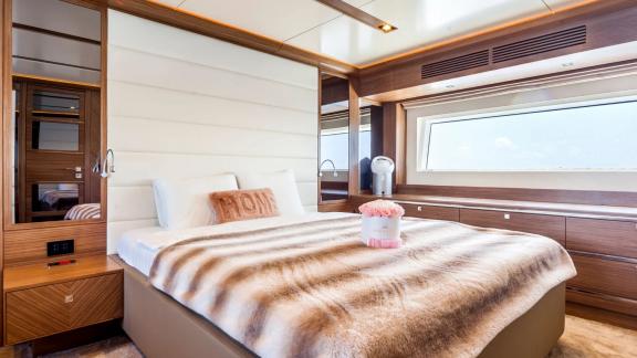 Large window, comfortable bed, and elegant wooden cabinets on Sirena 64.