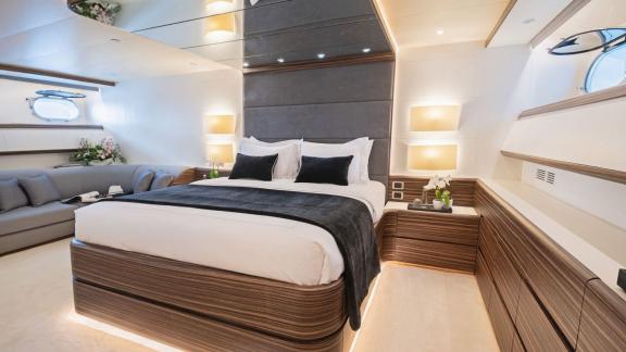 The cabin features a large bed with LED lights, dark headboard, seating area and wood finishes.