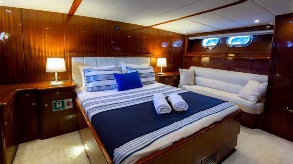 The master cabin of Sveti Sky features a double bed, side sofa and elegant wooden interior design.