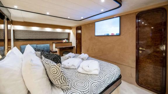 The VIP cabin of Wish Alfamarine 91 features a large bed, TV screen and wooden wall details.