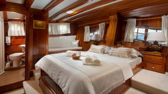 Elegant cabin of the Gulet Andi Star with comfortable double bed and wooden furnishings.