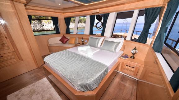 The spacious bedroom of the trawler Compass features large windows with views and a comfortable bed.