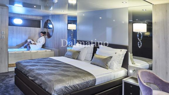 Luxuriöses Hauptschlafzimmer auf der Dalmatino-Yacht mit gemütlichem Bett und Jacuzzi im Hintergrund.