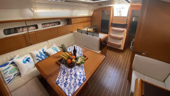 The saloon of the Mercann sailing yacht features a stylish table, white sofas, and a modern kitchen.