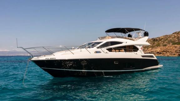 The motor yacht Midnight Summer Dream is anchored in clear waters, offering a serene view.