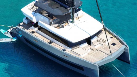 Вид с воздуха на катамаран Moonlight, стоящий на якоре в чистой бирюзовой воде.