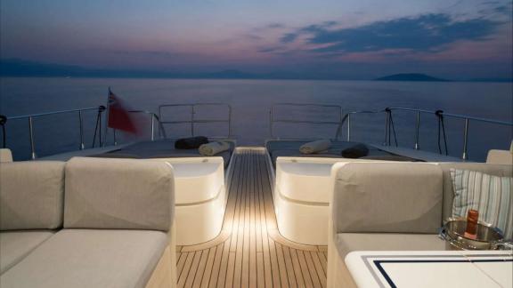 Zu sehen ist das beleuchtete Achterdeck der Atrato in Athen mit Sitz- und Liegebereichen bei Sonnenuntergang.