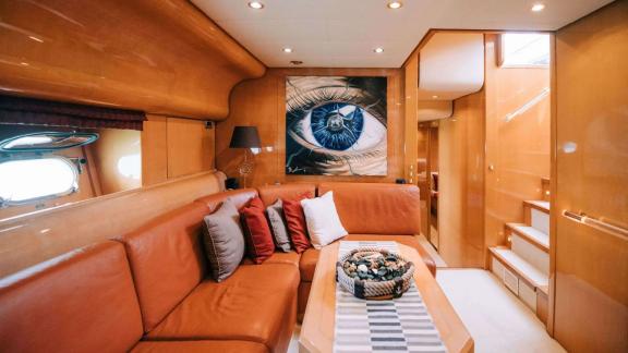 Zu sehen ist der Salon der Motoryacht Atrato in Athen mit Ecksofa, Tisch und Treppenaufgang.